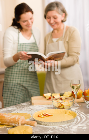 Apple pie recipe two women looking in cookbook happy baking Stock Photo ...