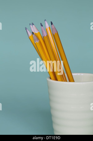 Sharpened pencils in cup on blue background Stock Photo