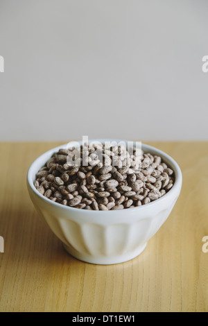 A white round china bowl of kidney beans on a table top Stock Photo