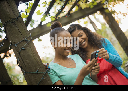 Scenes from urban life in New York City Two girls looking at a cell phone or computer pad laughing Stock Photo