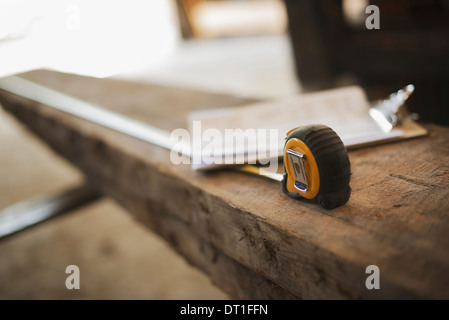 A reclaimed timber yard Recycled plank of wood measuring tape and a clipboard with paperwork Stock Photo