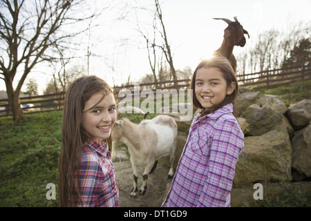 Two children young girls in the goat enclosure at an animal sanctuary Stock Photo
