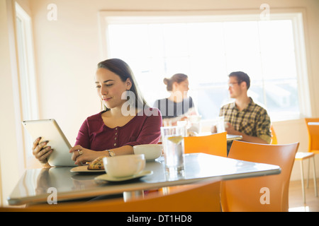 A woman in a coffee shop reading using a tablet computer Stock Photo