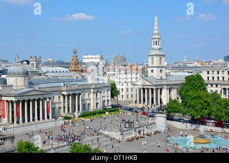 Aerial view tourists & people blue sky day in Trafalgar Square includes National Gallery colonnade spire of St Martin in the Fields London England UK Stock Photo