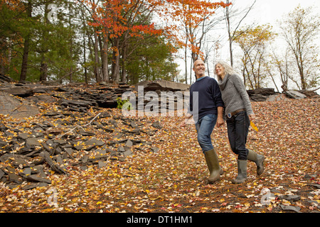 A couple man and woman on a day out in autumn walking through fallen leaves Holding hands