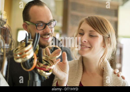 Two people a man and woman looking at the objects displayed on a mannequin hand antique jewellery and objects Stock Photo