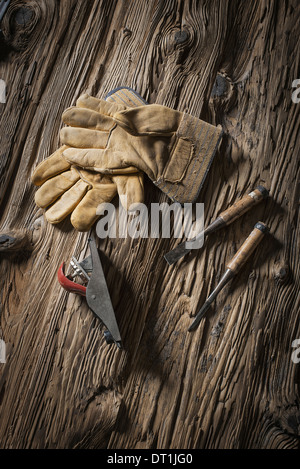A reclaimed lumber yard workshop A pair of leather working gloves and handheld traditional tools Stock Photo