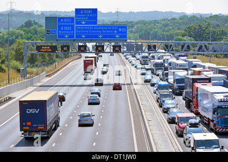 Gantry sign  spanning eight lane M25 motorway at junction 28 with electronic digital display warnings & gridlocked traffic Stock Photo