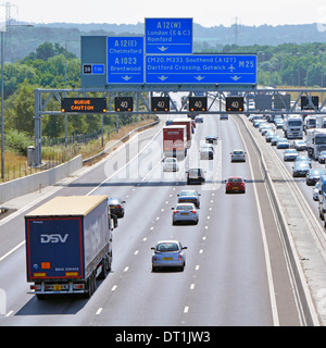 Gantry sign  spanning eight lane M25 motorway at junction 28 with electronic digital display warnings & gridlocked traffic Stock Photo