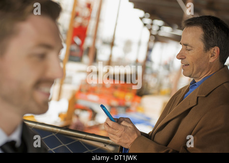 Professionals on the go keeping in contact using mobile phones and talking to each other Two men Stock Photo