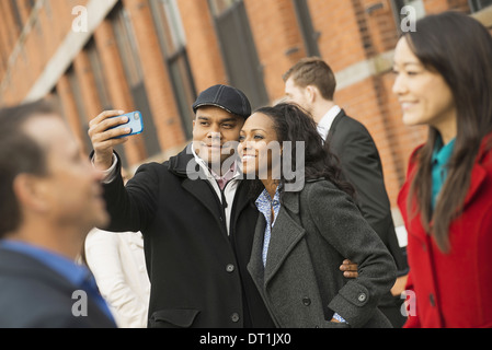 People keeping in contact using mobile phones A man holding out a camera phone and taking photograph Stock Photo