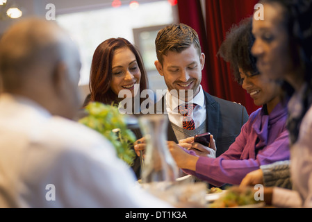 using mobile phones and talking to each other In a coffee shop Stock Photo