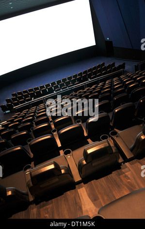 Interior of cinema auditorium seen from the top with rows of seats and blank white cinema screen in front Stock Photo