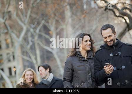 Couple walking in urban park with smartphone Stock Photo