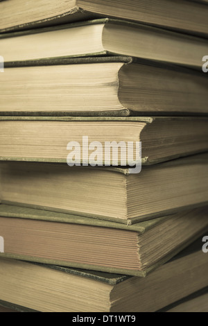 A stack of old hard cover books with worn edges and aged yellowing paper Stock Photo