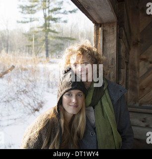 Two people a mother and daughter side by side in the porch of a wooden barn on a farm A winter's day Stock Photo