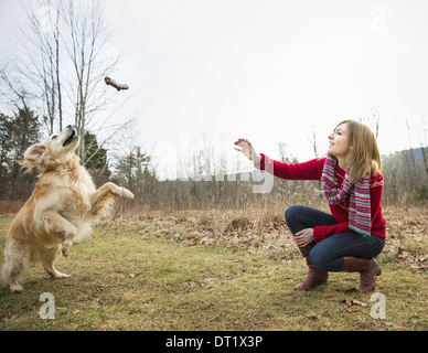 A young woman outdoors in the winter on a walk with a golden retriever dog Stock Photo