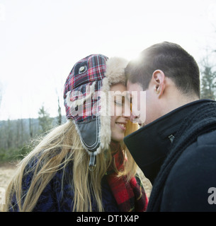 A couple young man and woman face to face embracing outdoors on a cold winter day