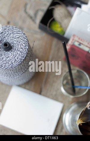 A table top with a small group of objects Tankard and pencils paper and a large ball of string Stock Photo