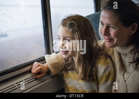 A man and a young girl sitting beside the window in a train carriage looking out at the countryside Smiling in excitement Stock Photo