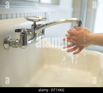 A boy washing his hands under the bathroom tap Stock Photo