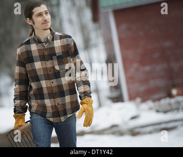 An organic farm in winter in New York State USA A man in a plaid shirt walking across snow-covered ground Stock Photo