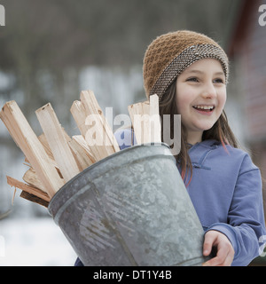 An organic farm in winter in New York State USA A girl carrying a bucket full of kindling and firewood Stock Photo