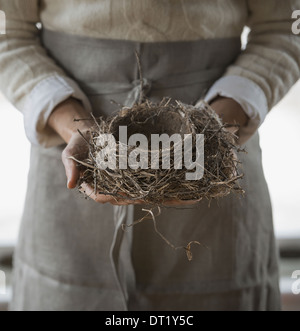 An organic farm in winter in New York State USA A woman in a work apron holding a woven twig bird nest Stock Photo