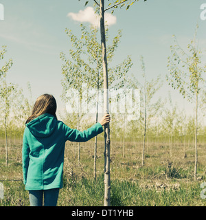 Ten year old girl standing next to commercially grown poplar tree on large tree farm near Pendleton Oregon Stock Photo