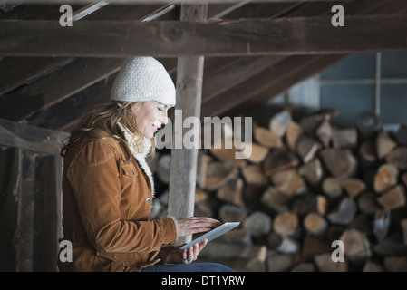 An organic farm in upstate New York in winter A woman sitting in an outbuilding using a digital tablet Stock Photo