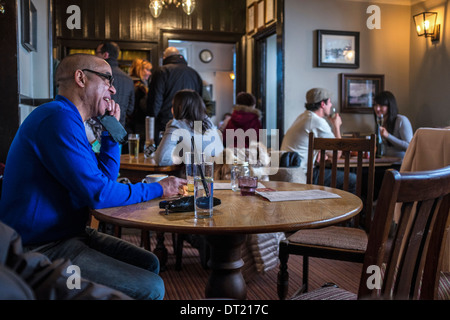 Interior of White Cross Pub with people relaxing and man using mobile phone, Richmond upon Thames, Surrey, Southwest London,England, UK Stock Photo