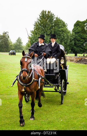 Wedding horse and carriage departing from a venue in private parkland in the rain Stock Photo