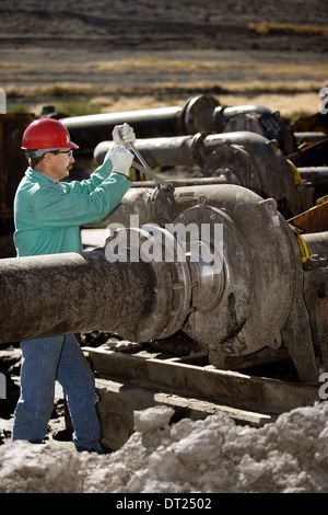 A laborer performs maintenance on an industrial pumping station. Stock Photo