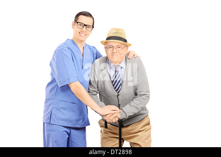 Male healthcare professional assisting an old man with cane Stock Photo