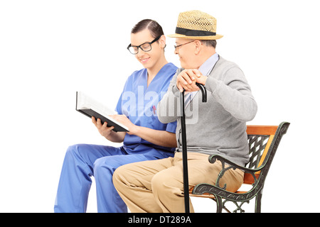 Male healthcare professional reading to a senior gentleman seated on bench Stock Photo