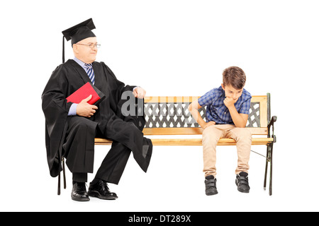 Mature college professor and a thoughtful kid seated on bench Stock Photo