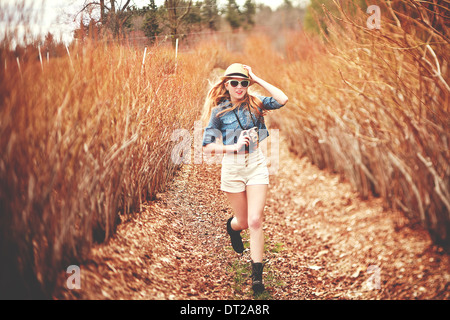 Young woman in fedora hat running towards camera