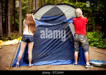 Rear view of young woman and man pitching tent Stock Photo