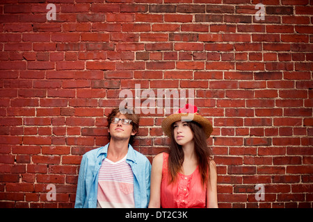 Portrait of young couple standing in front of brick wall Stock Photo