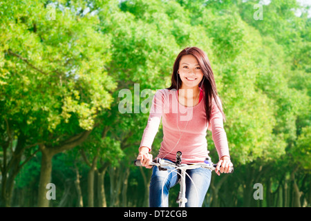 young woman riding bike and listening music Stock Photo