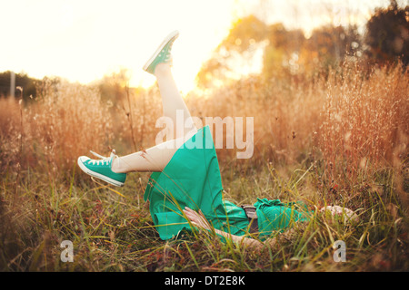 Teenage girl lying in grass at sunset Stock Photo