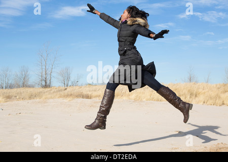 USA, Illinois, Waukegan, Young woman running on sand
