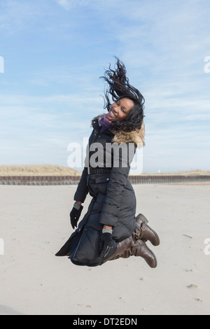 USA, Illinois, Waukegan, Young woman jumping on beach Stock Photo