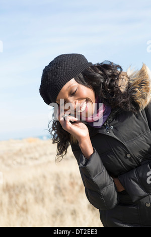 USA, Illinois, Waukegan, Portrait of young woman standing in grass and using mobile phone