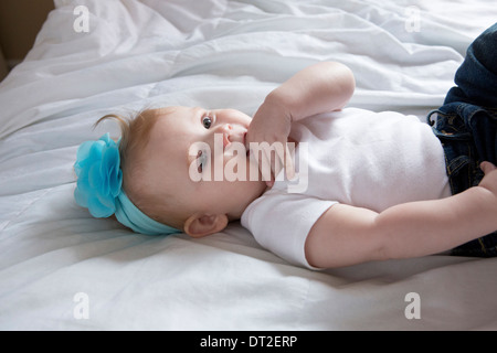 Portrait of baby girl (6-11 months) lying down on bed Stock Photo