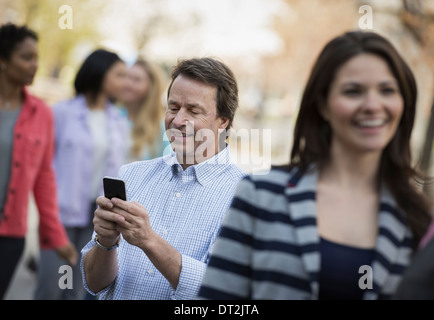 People outdoors in the city in spring time A man checking his cell phone among Stock Photo