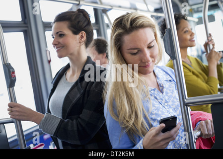 New York City men and women on a city bus Public transport Keeping in touch A young woman checking or using her cell phone Stock Photo