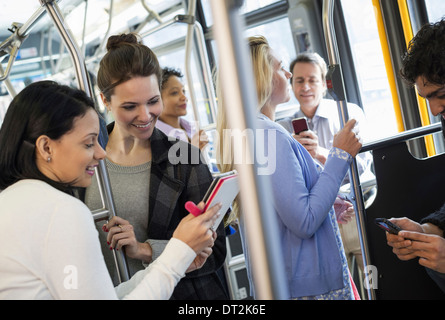 New York City People men and women on a city bus Public transport Two women looking at a handheld digital tablet Stock Photo