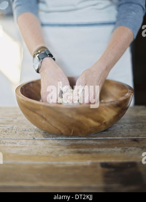A domestic kitchen A cook preparing pastry mixing it by hand on a tabletop Stock Photo