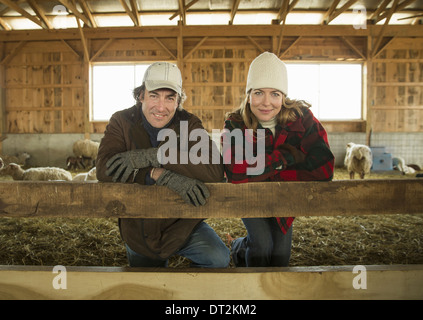 An Organic Farm in Winter in Cold Spring New York State A farmer and a woman standing by a pen full of sheep Stock Photo